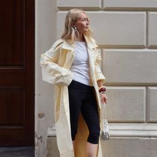 woman wears yellow trench coat, white T-shirt and black capri pants