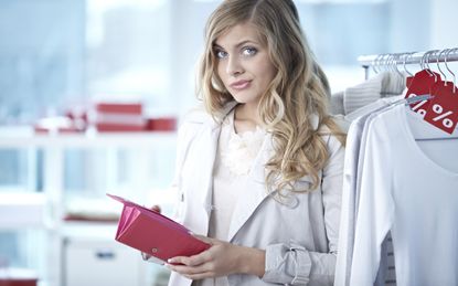 Confused woman holding empty wallet in clothing store