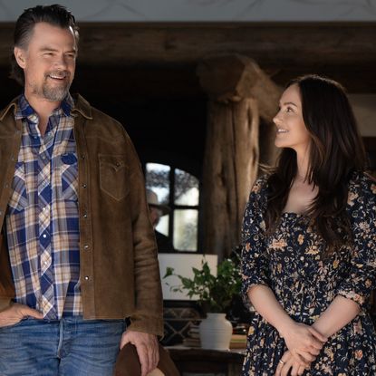 josh duhamel as staten and minka kelly as quinn looking at each other smiling in a ranch home in ransom canyon