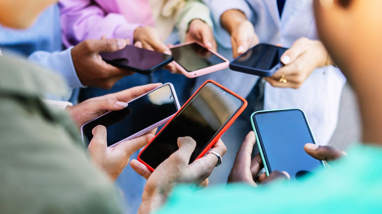 A group of people using their cell phones stand in a circle