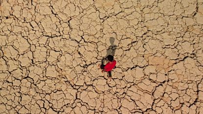 A youth walks on cracked and dried up soil in Iraq