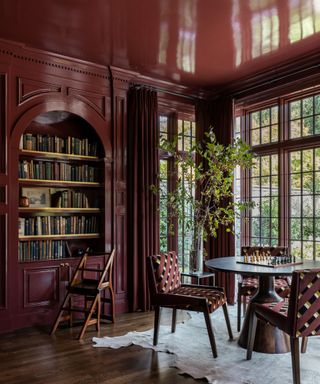 dark red library room with round table and large window