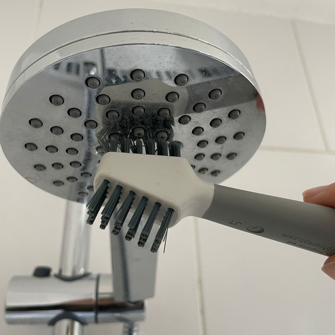 Using the Joseph Joseph cleantech detail brush to clean a shower head