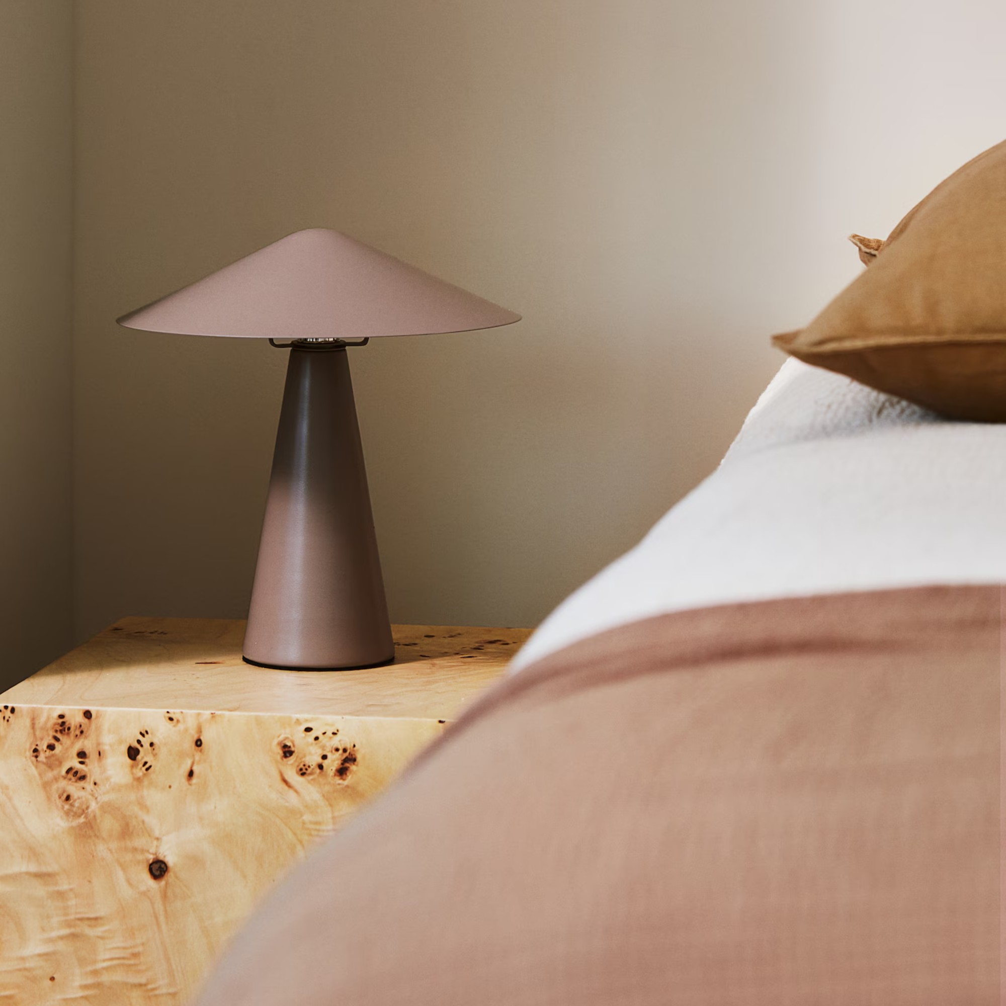 H&M Metal table lamp in mole on a block bedside table with tonal bed linen on the bed next to it