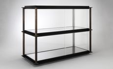 A bronze skeleton cabinet supported by blackened steel trays and strengthened ribbed glass panels