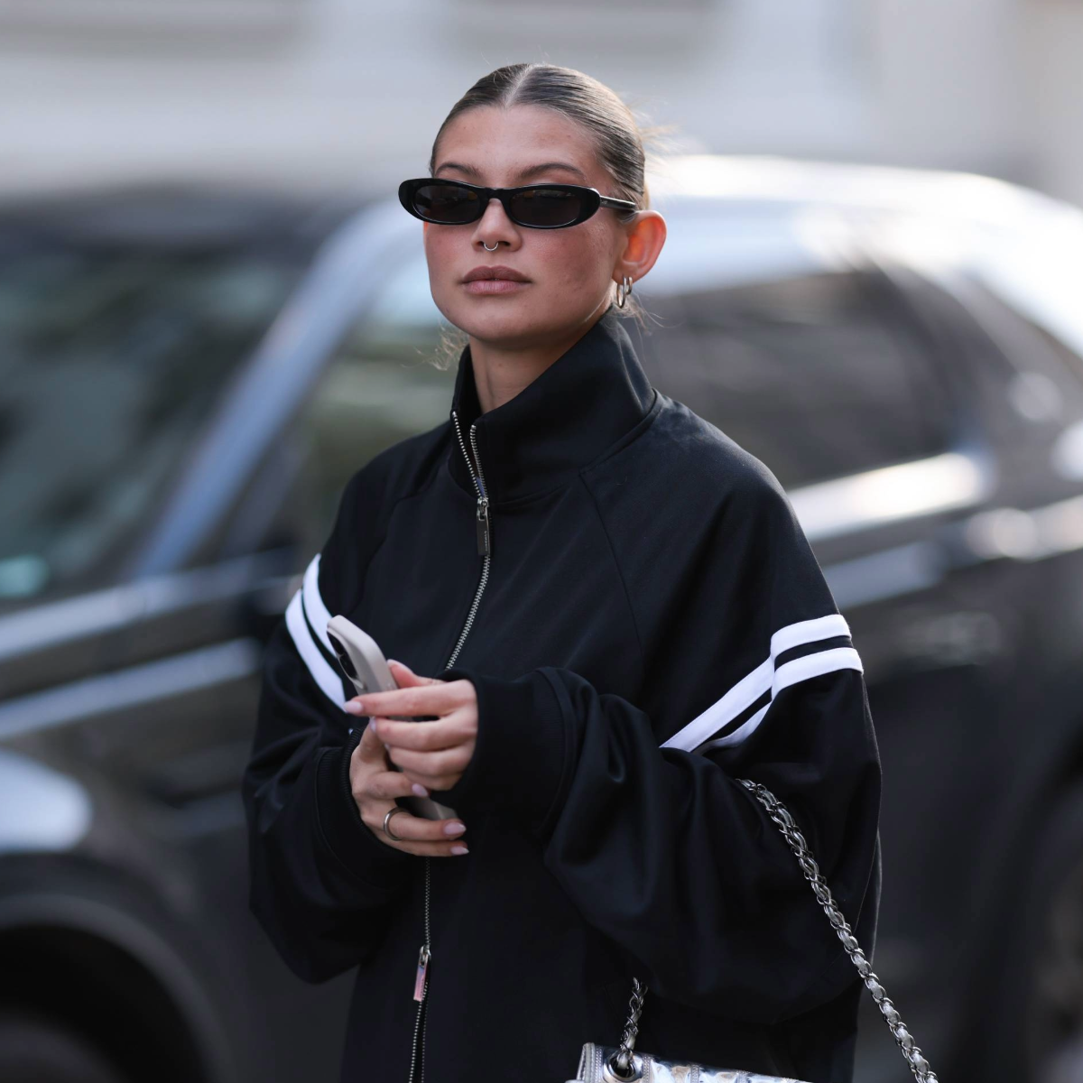 woman wearing a track jacket and glasses and a slick-back bun 