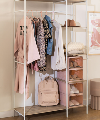 A white clothing rack with pink shoebox storage and a neutral and denim selection of clothing