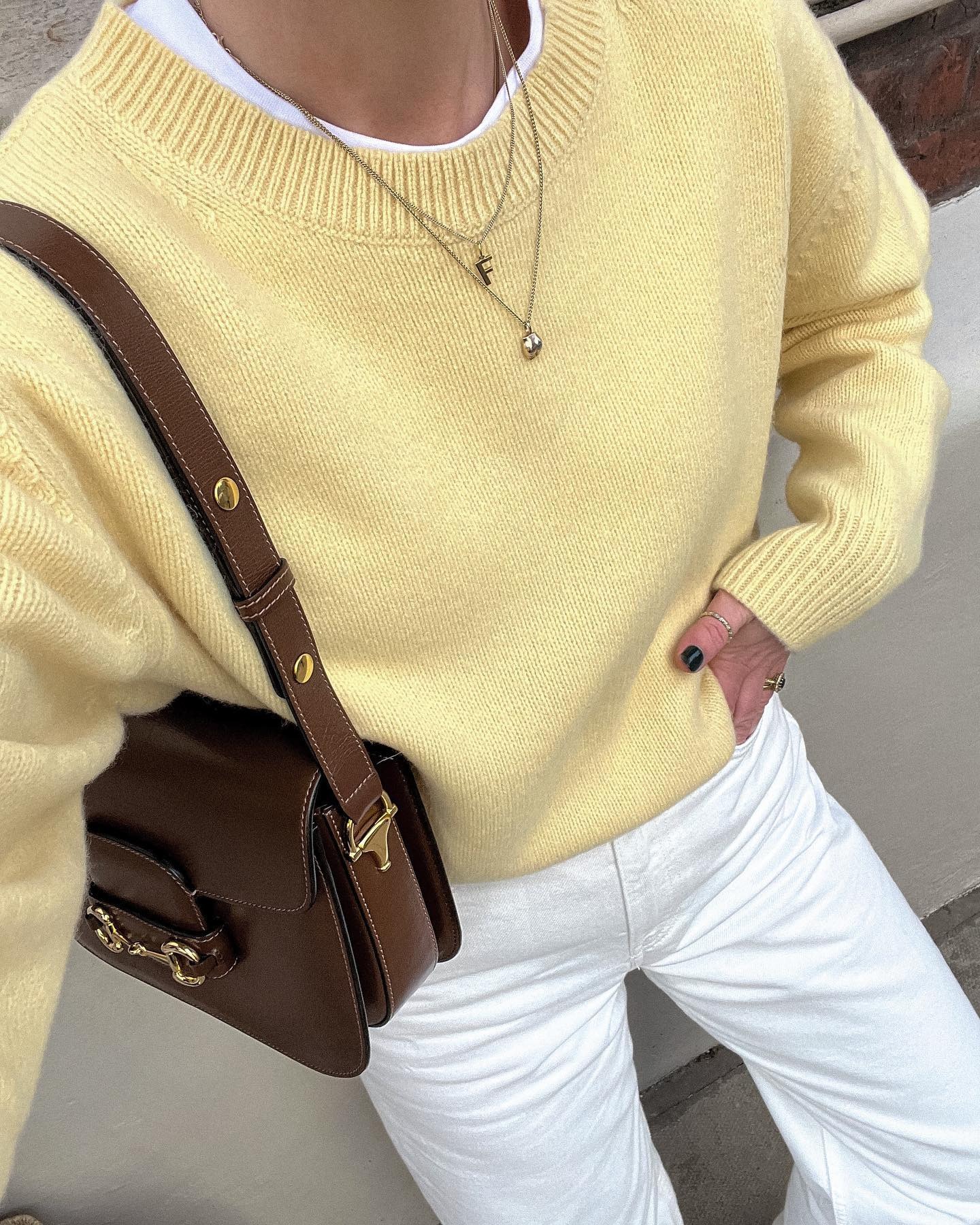Woman wears yellow jumper, white jeans and brown gucci bag