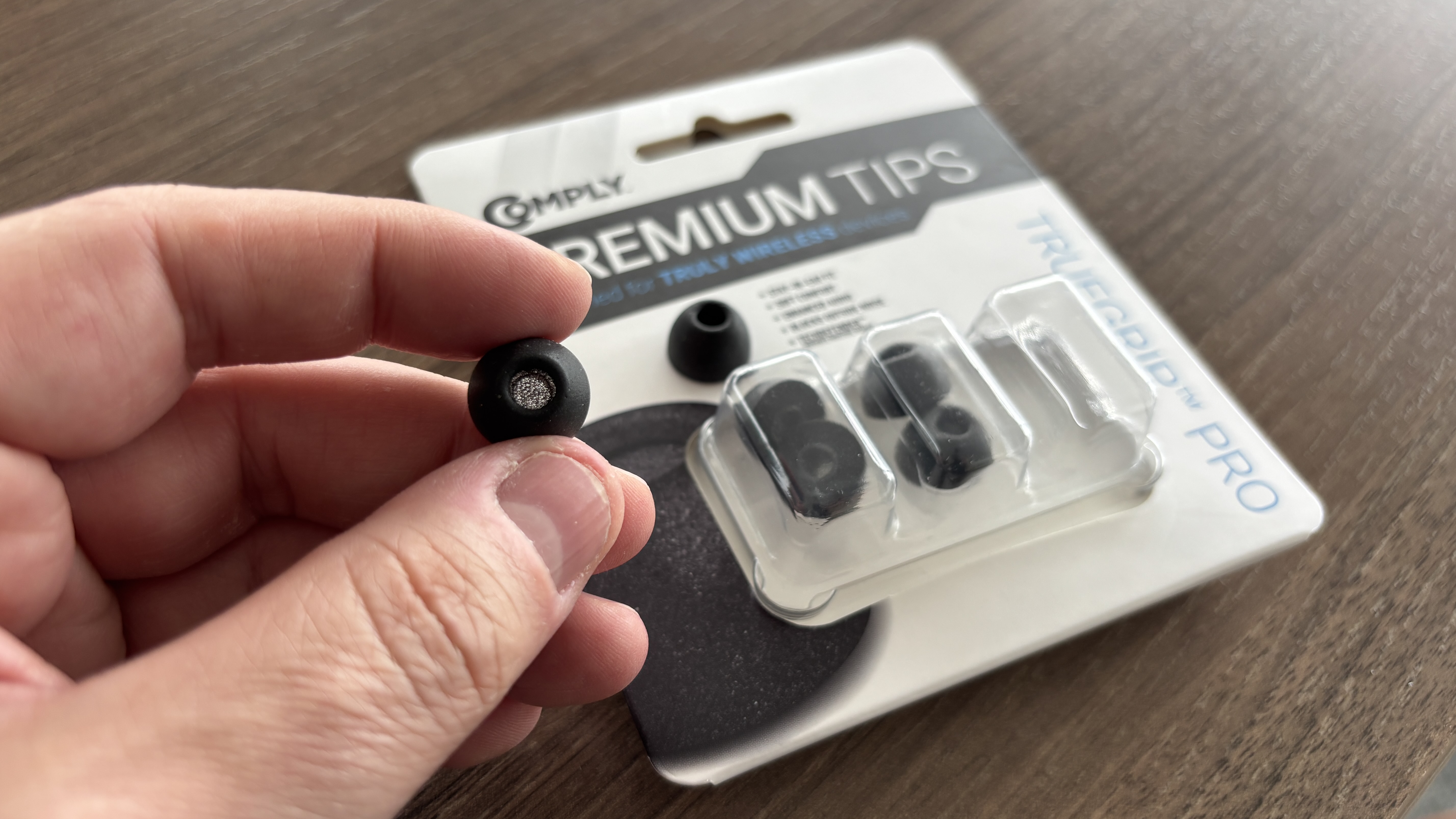 Comply Truegrip Pro eartips being held in a hand next to their box