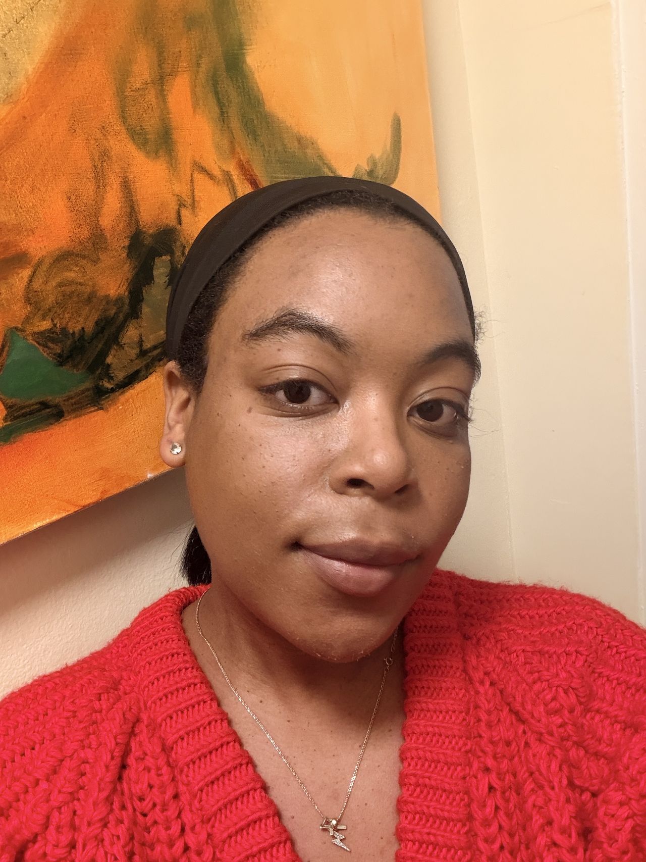 Ariel Baker after using the Hourglass Finishing Powder in Radiant Light in a bright red sweater.