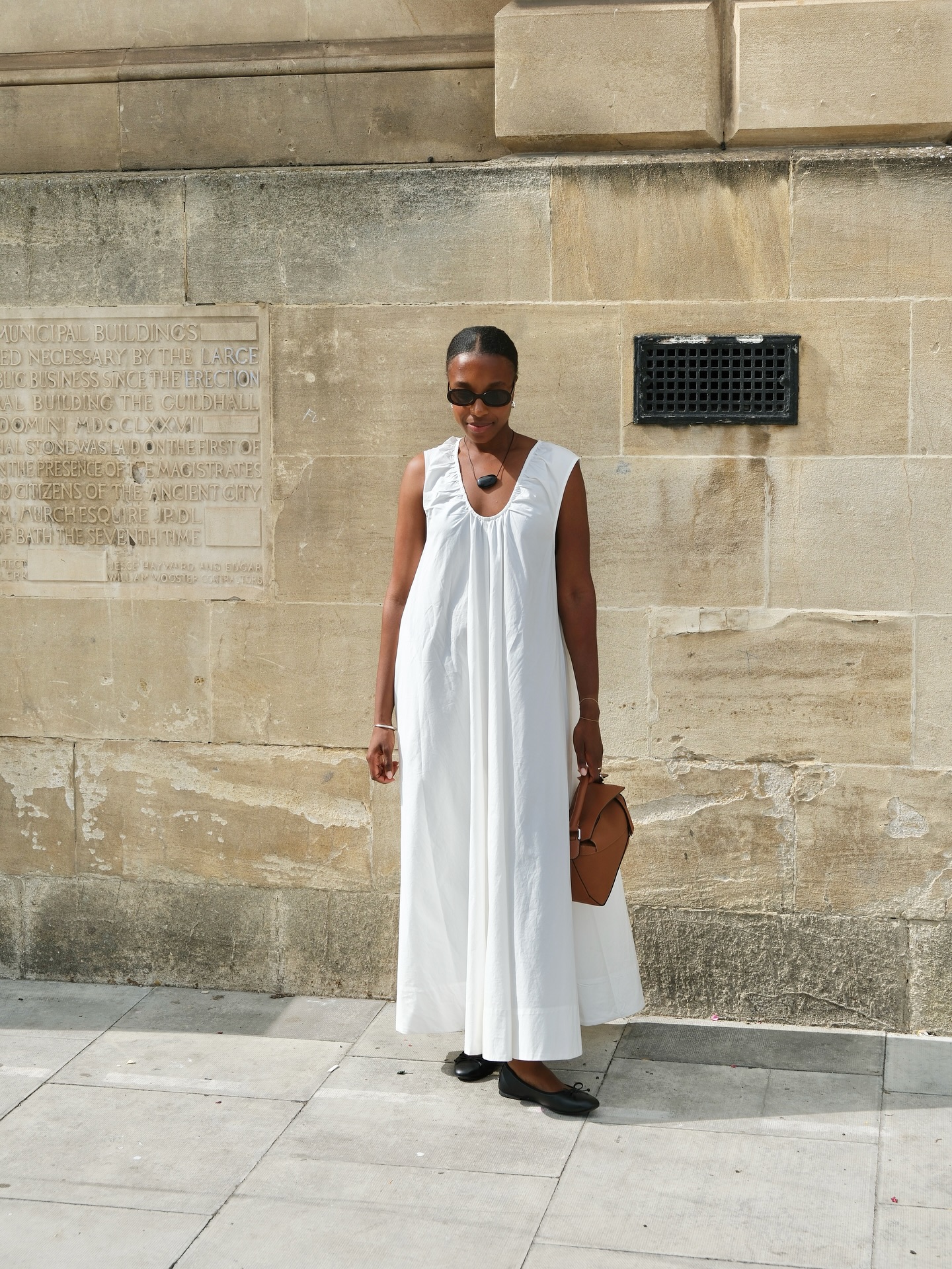 An image of influencer @taffymsipa wearing a white DISSH dress with a Loewe puzzle bag and black ballet flats.