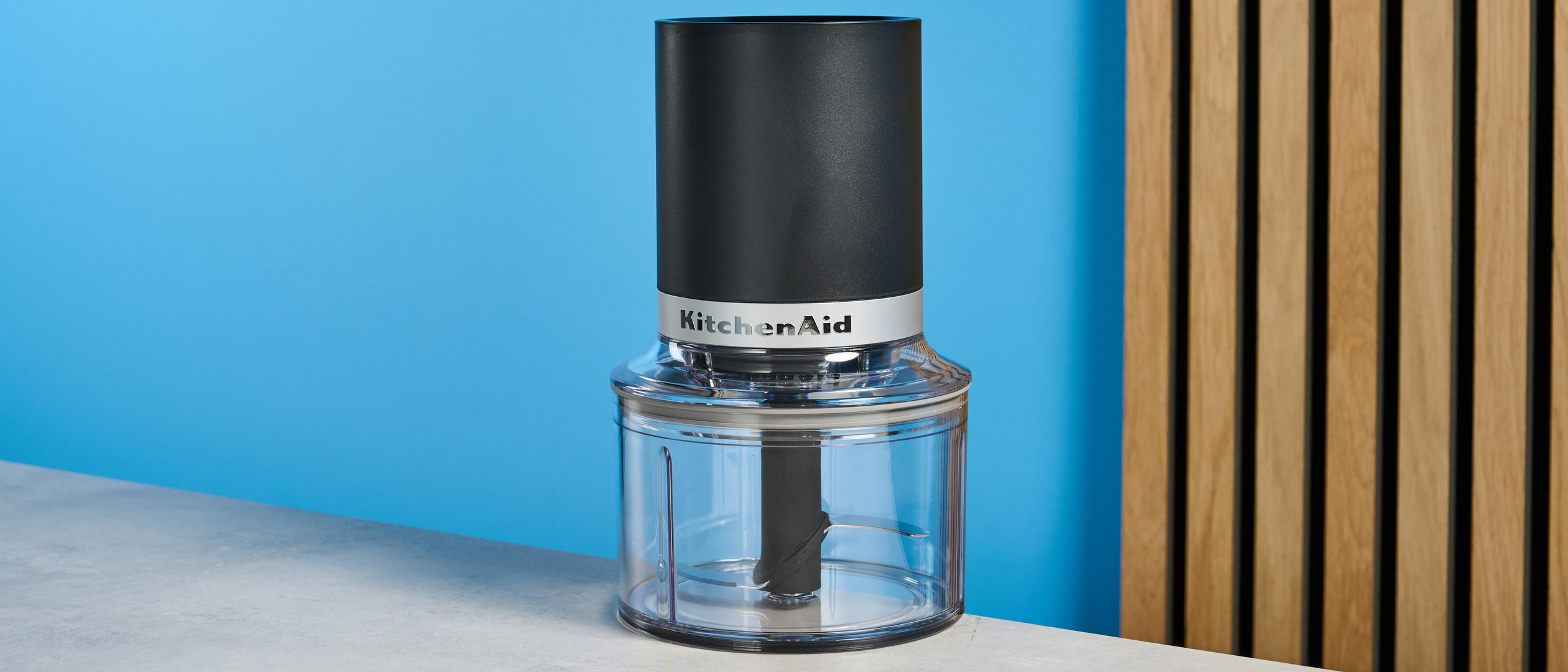 KitchenAid Cordless Top Down Food Chopper photographed in front of a blue background.