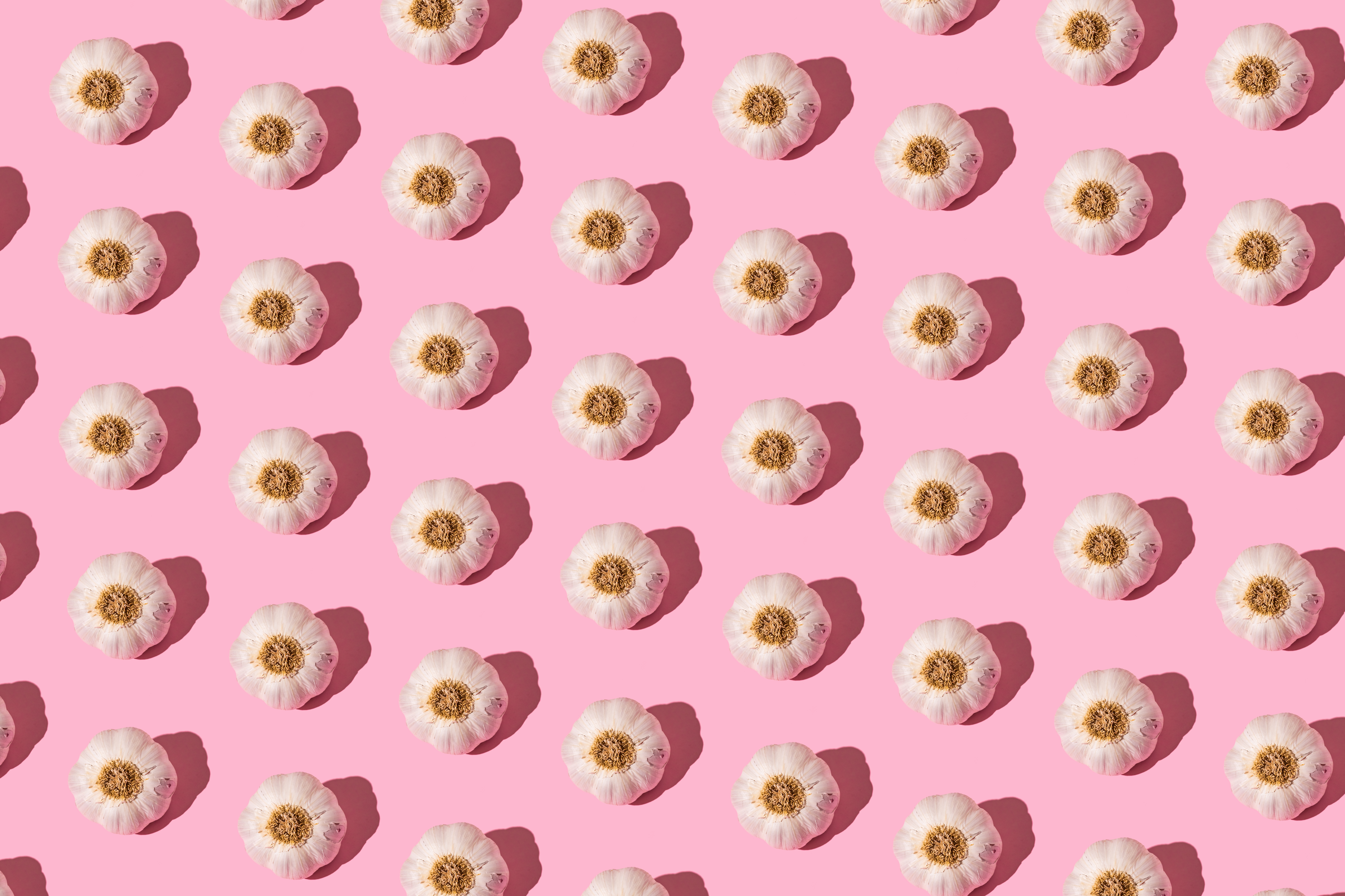 Repeated pattern of garlic bulbs on a pink background