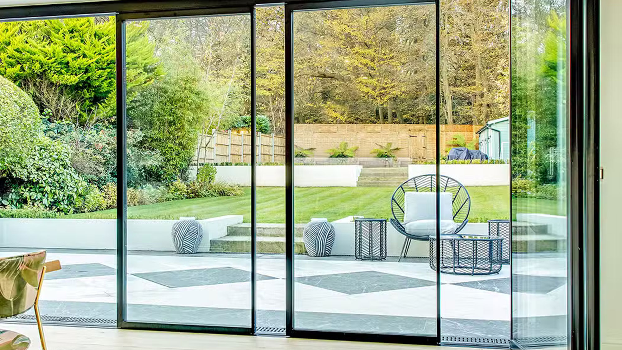 modern sliding glass doors leading out to a paved patio space with a lawn beyond