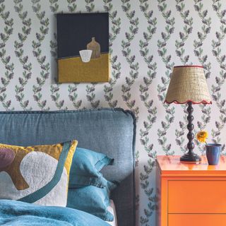 bedroom with floral wallpaper, orange bedside table and bobbin lamp