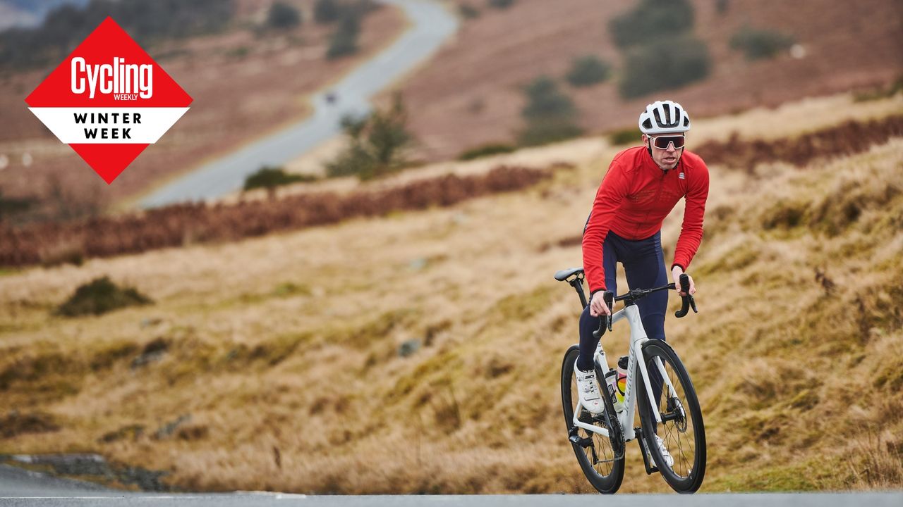 Rider in black tights and red jersey riding on the road with heath background