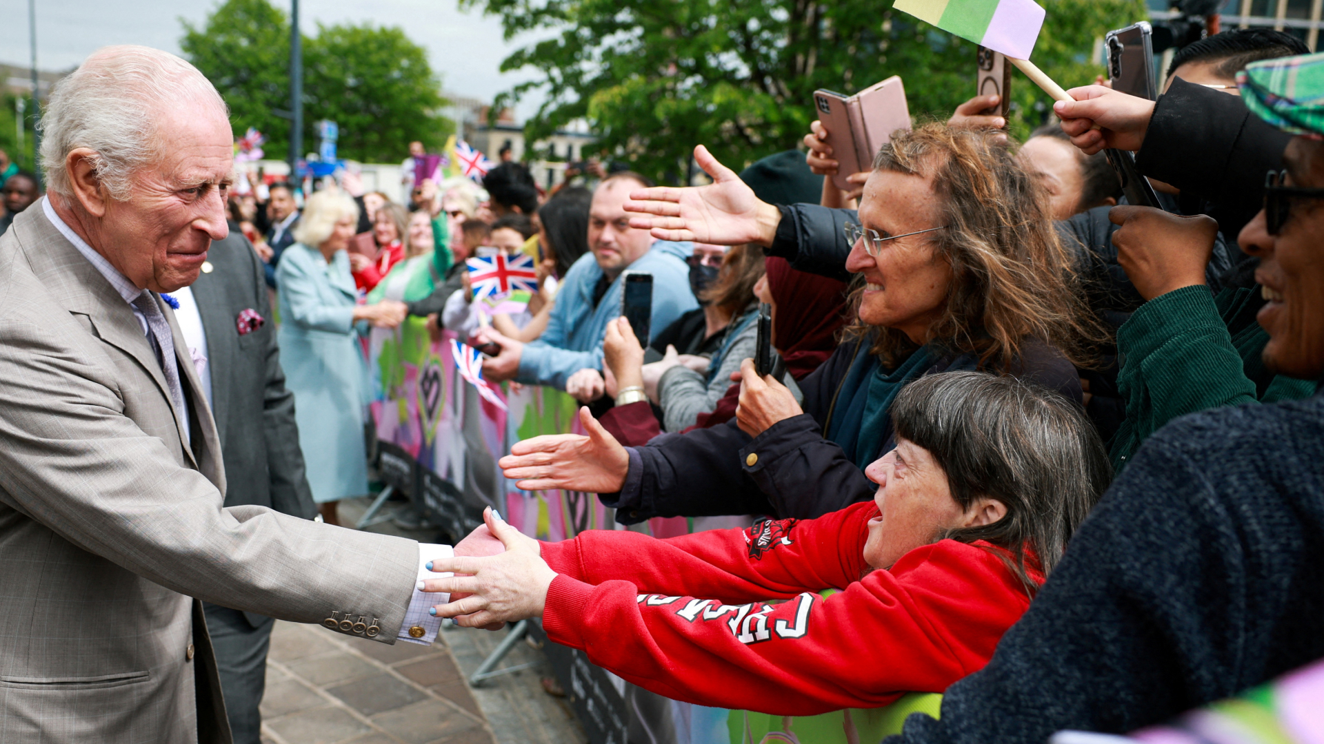 King Charles shaking hands with a crowd wearing a gray suit