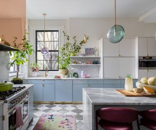 A light blue and white kitchen with marble countertops, a black and white checkerboard floor, and a copper range hood