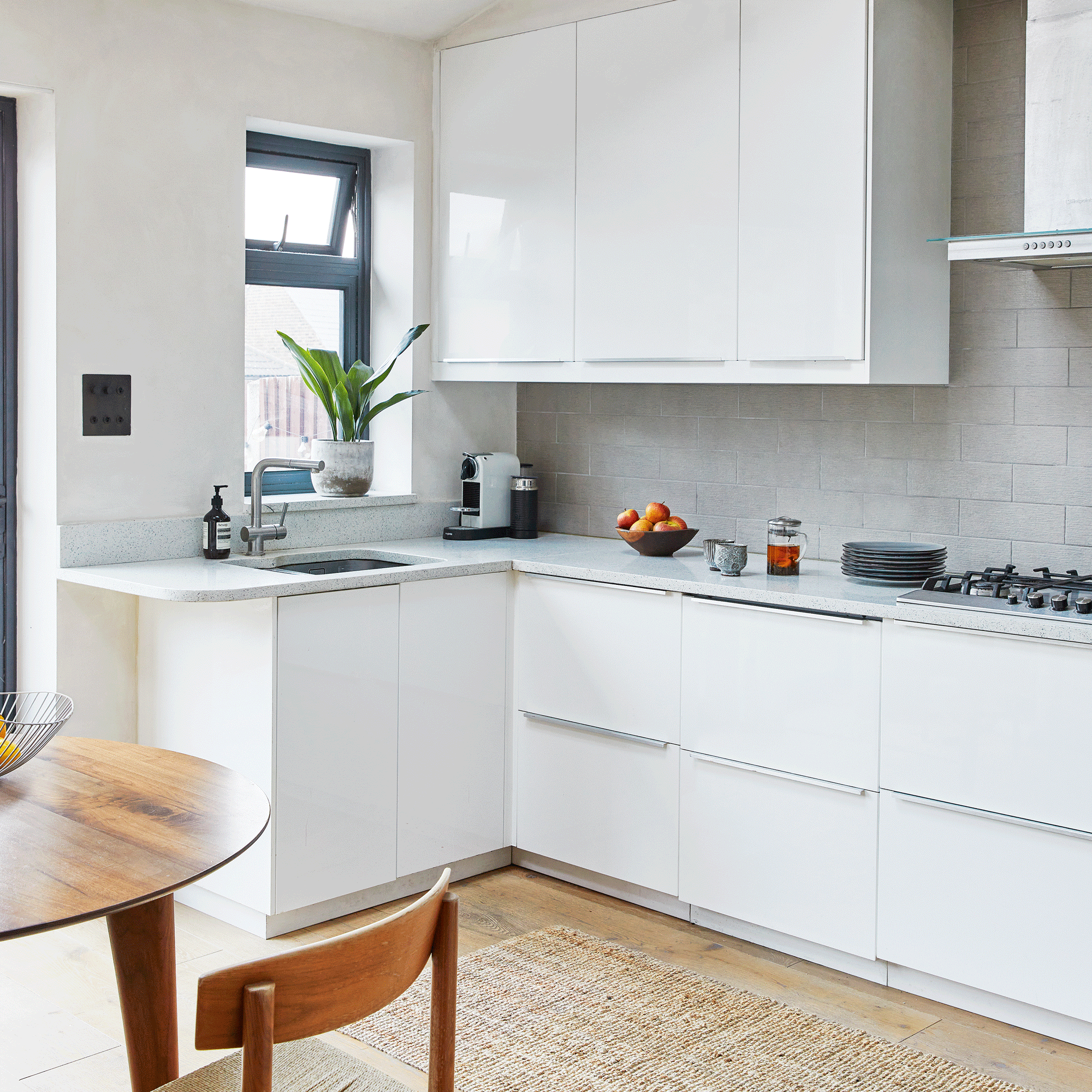an open plan kitchen diner with modern white cabinets and metro tiled splashback beside a vintage dining table and chairs