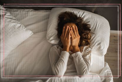 A woman lying in bed with her hands over her face