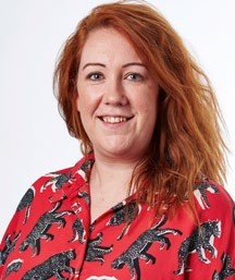 Portrait of Sarah, the in-house expert at Ideal Home, wearing a red shirt with animal prints, smiling against a light background.