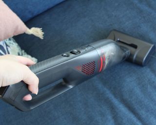 Eufy HomeVac H30 Infinity vacuum cleaner picking up pet hair on dark blue upholstered sofa