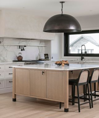 A kitchen with marble counters, a spherical light fixture and a large kitchen island