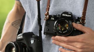 Two cameras on straps around a man's neck