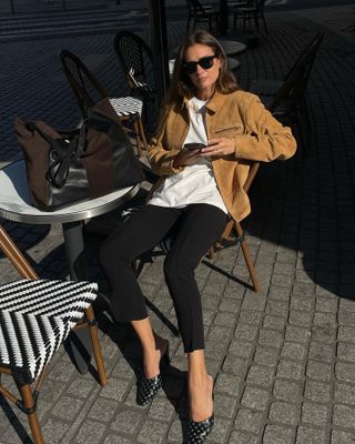 Die französische Mode-Influencerin Anne-Laure Mais trägt in Paris ein schickes Herbstoutfit mit schwarzen Hosen.