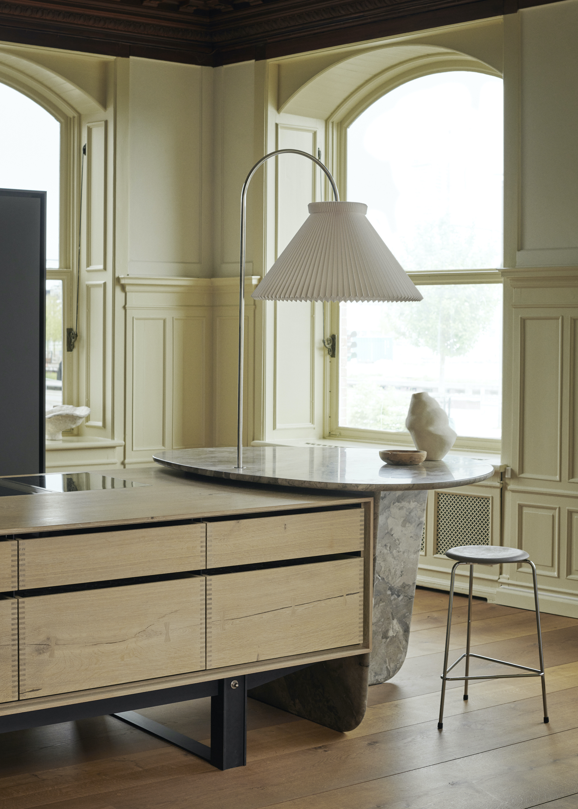 Kitchen with island with round marble bar and large lamp above