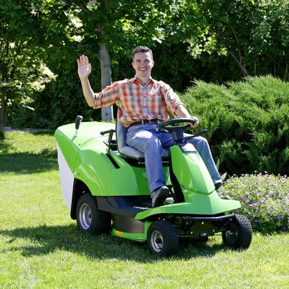 Man riding a lawn mower waving on a sunny day