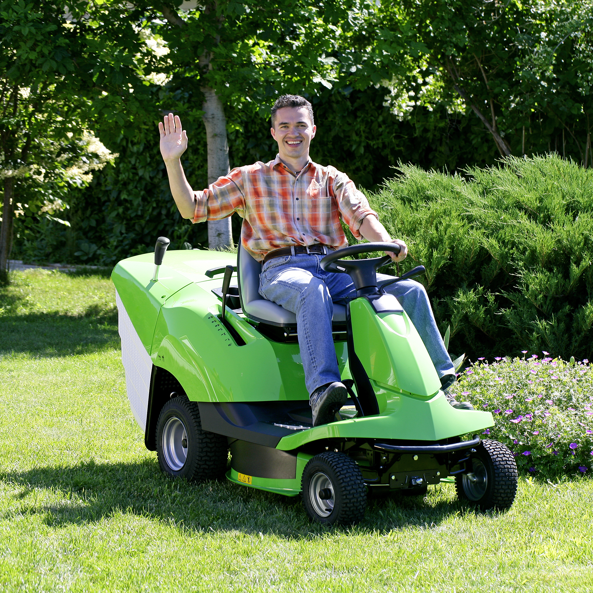 Man riding a lawn mower waving on a sunny day