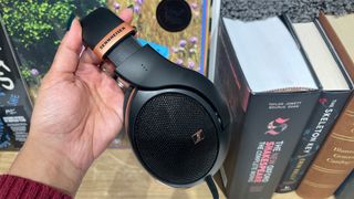 Sennheiser HD 505 open-back headphones held in hand over bookshelf