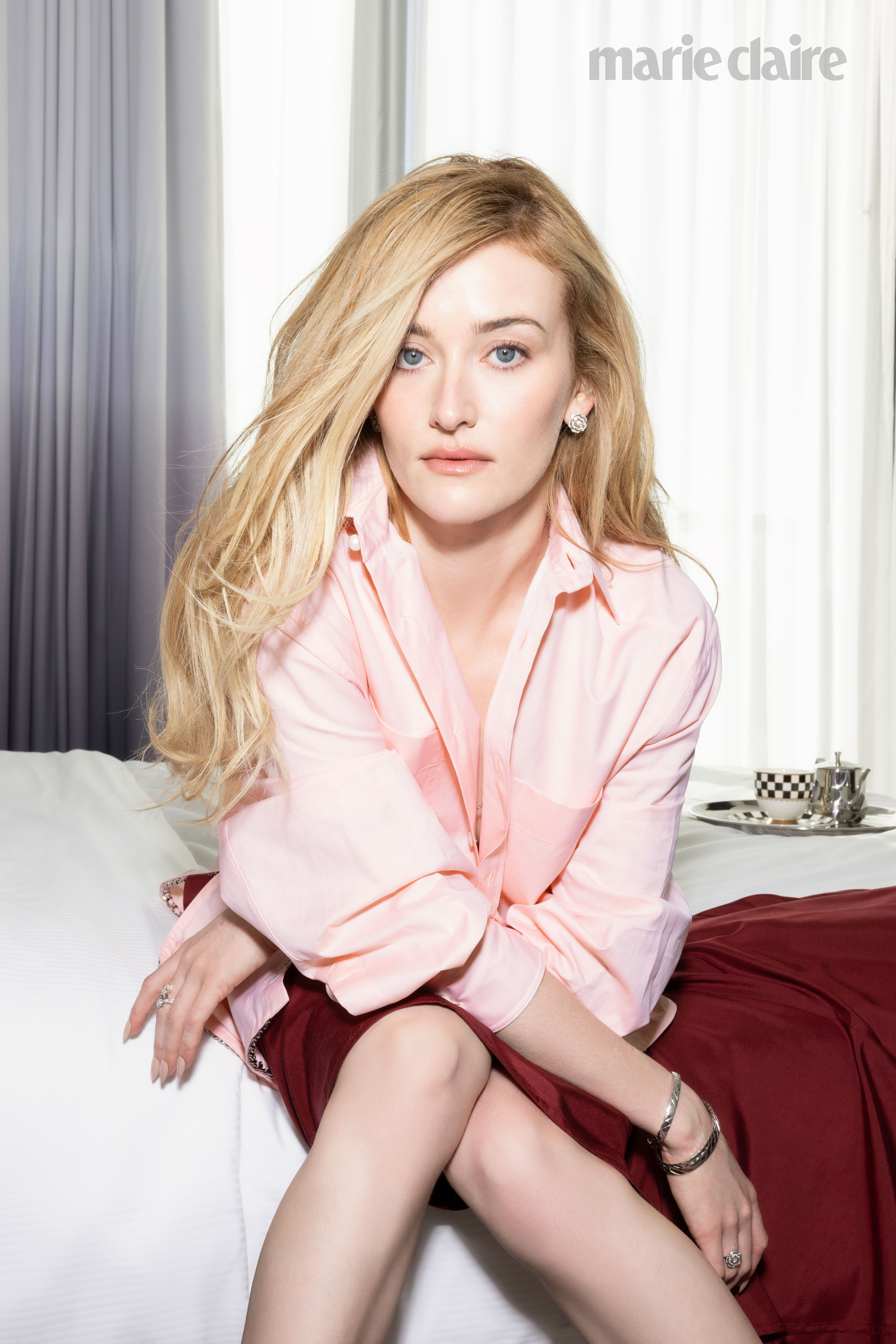 Sarah Pidgeon wearing a pink top and scarlet skirt in a hotel room