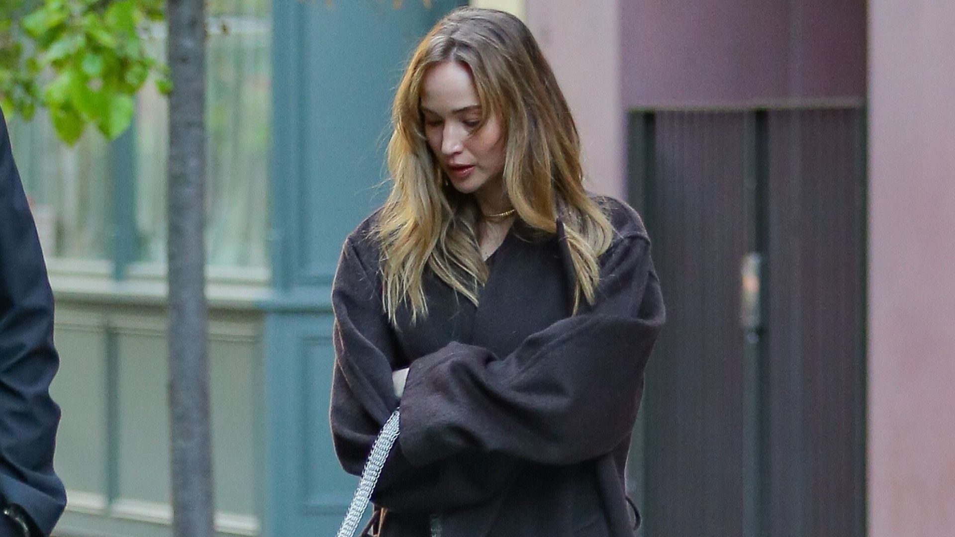 Jennifer Lawrence wears black satin kitten heels with a brown coat and a silver sparkly bag.