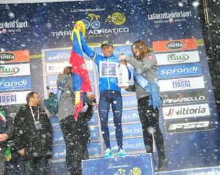 Snow falls as Quintana celebrates on the podium.