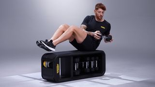 Man on a Technogym bench performing a dumbbell oblique twist