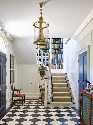 large entryway with chequered black and white flooring, blue doors, white walls, brass lantern