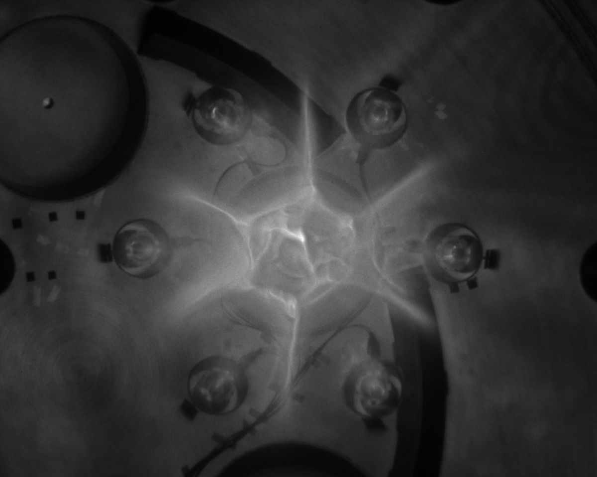 Seven supersonic jets of plasma collide during an early test firing of the Plasma Liner Experiment.