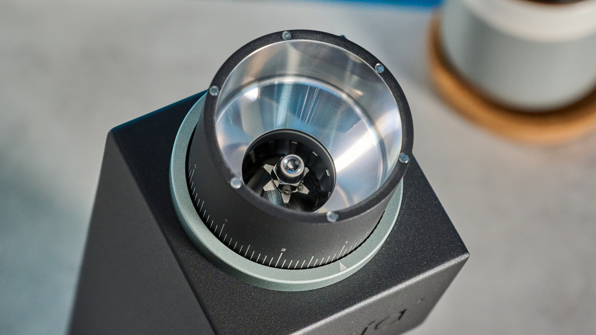 The Varia VS3 coffee grinder in use on a stone surface with a blue background