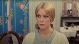 Catherine Deneuve looks forward with a stern expression in The Umbrellas of Cherbourg.