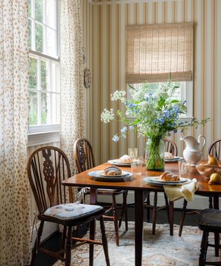 Breakfast nook with striped walls, Wood table and dining chairs with spring flowers and breakfast food