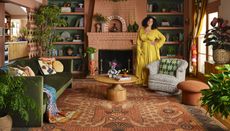Justina Blakeney in a yellow wrap dress in a living room with boho elements and a pink and green palette