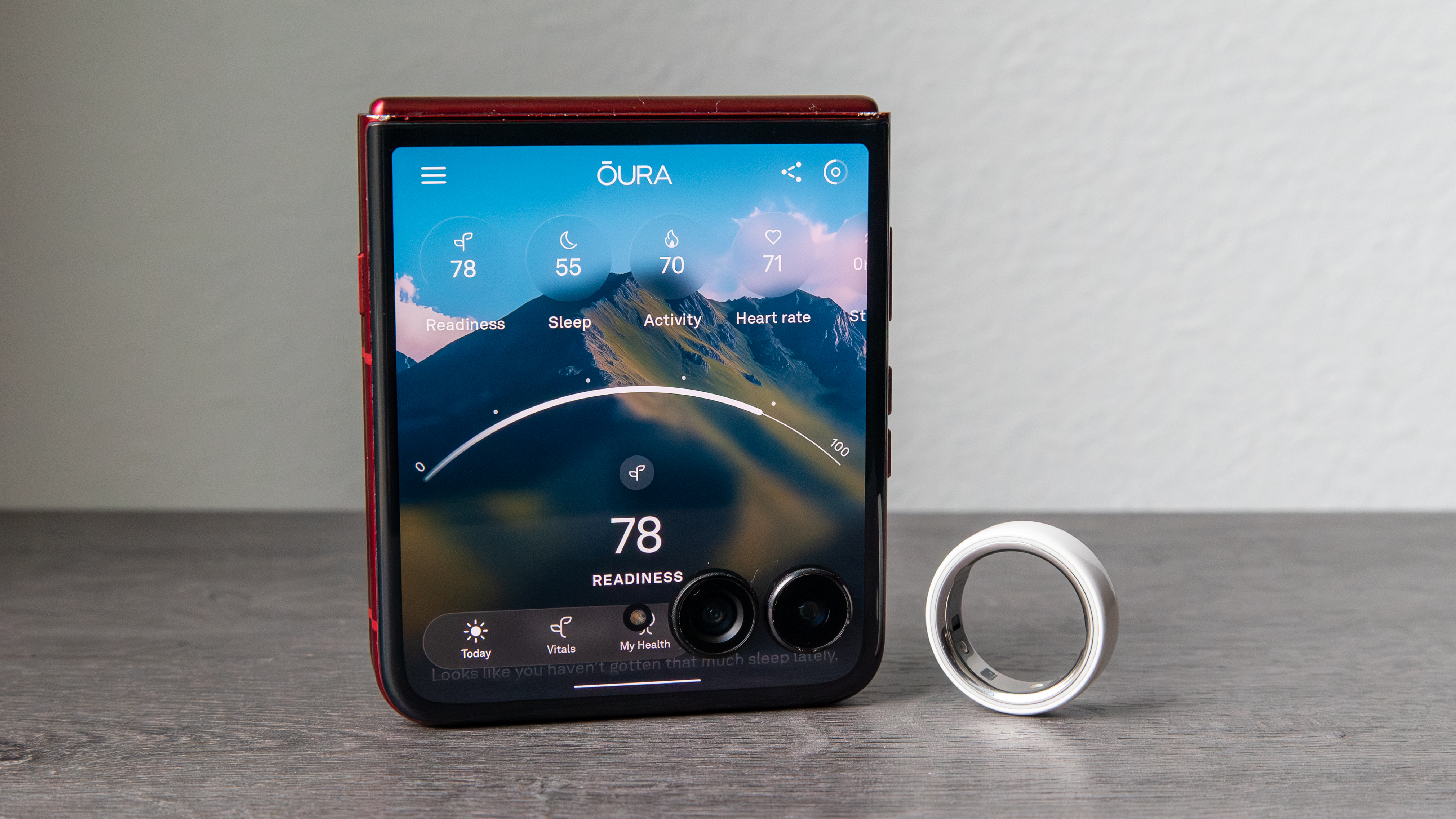 Oura Ring 4 Ceramic next to a phone with the Oura app