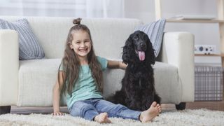 Girl smiling sitting on floor with cocker spaniel