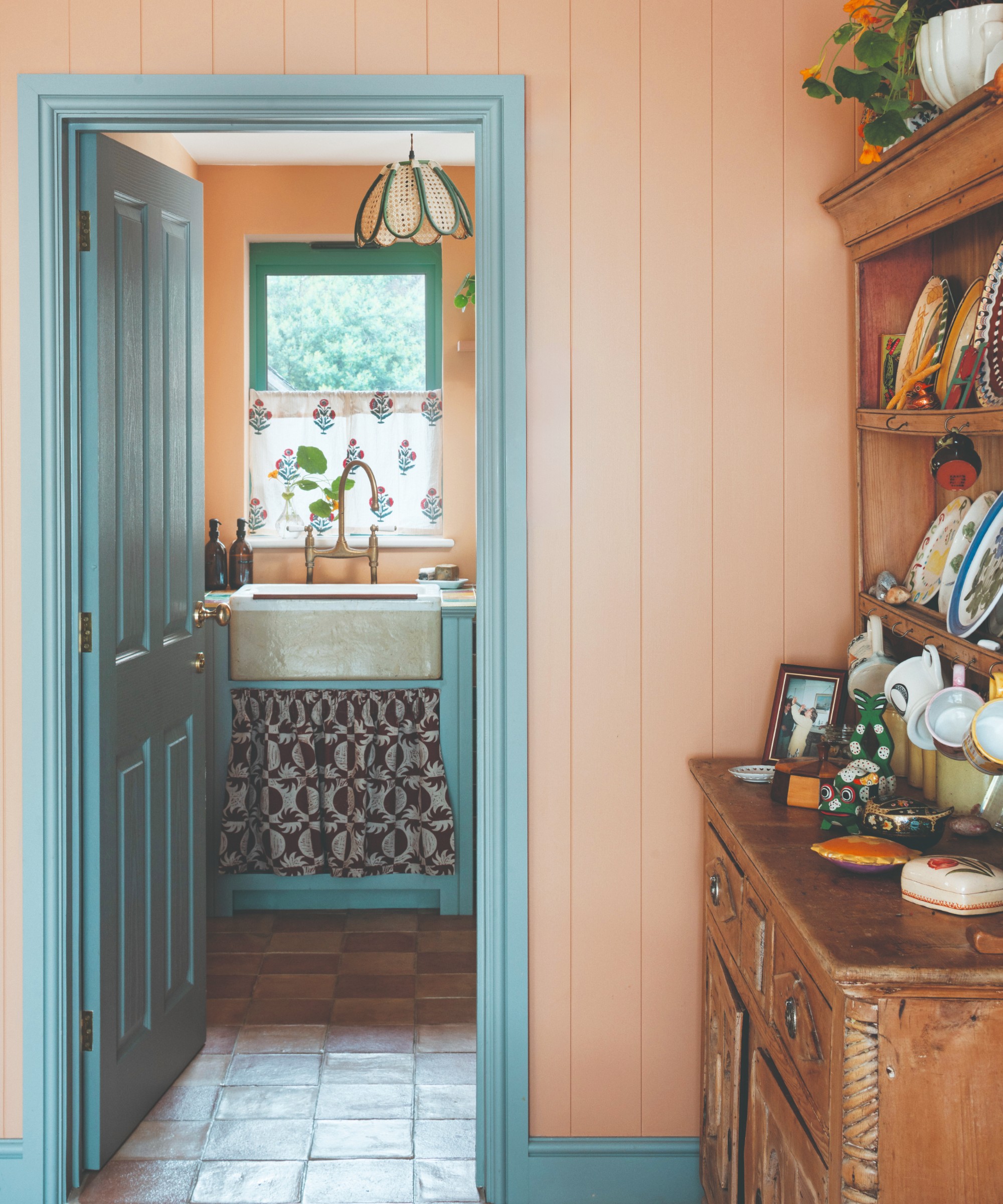 A wall covered in wide tongue and groove panelling in coral with a door, door frame and skirting boards painted in contrasting sky blue