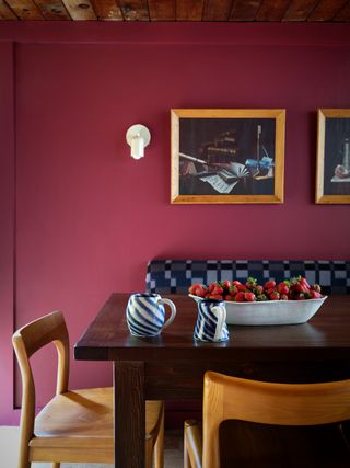 dining room with burgundy paint, timber ceiling, blue banquette seat and timber chairs around dining table