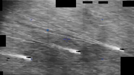 Three ships on a gray sea spot a hovering object in this DoD video