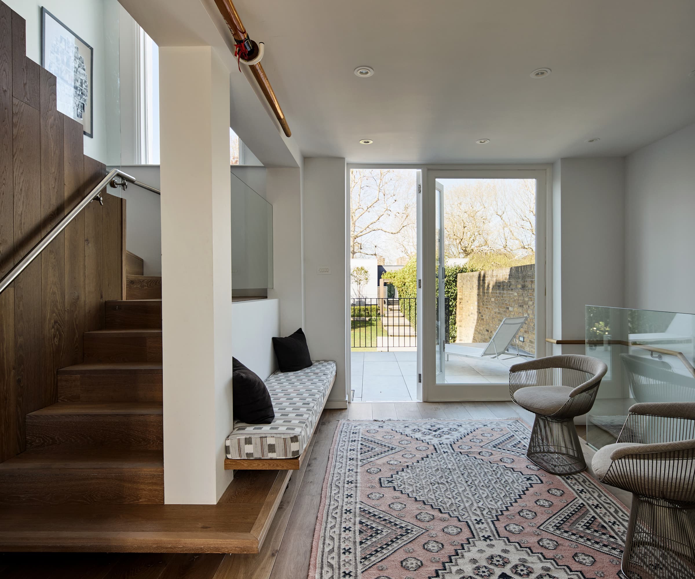 A wooden staircase with a seating area leading to bifold doors