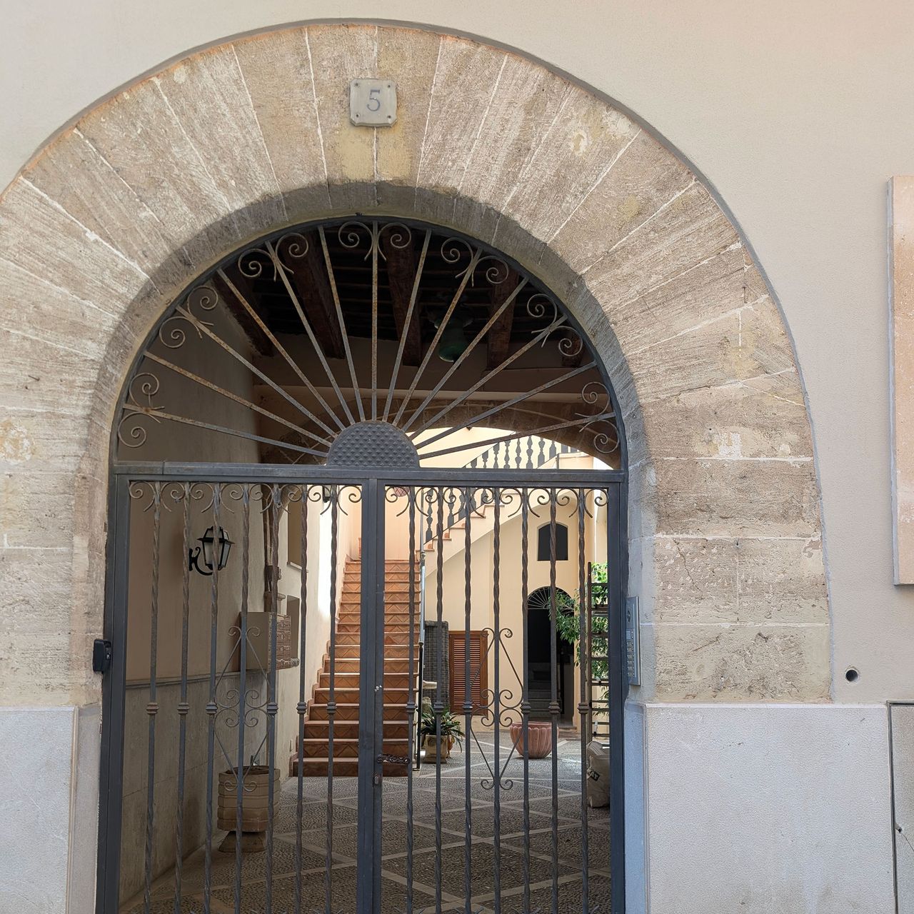 Stone building with arched doorway with steel door showing atrium inside